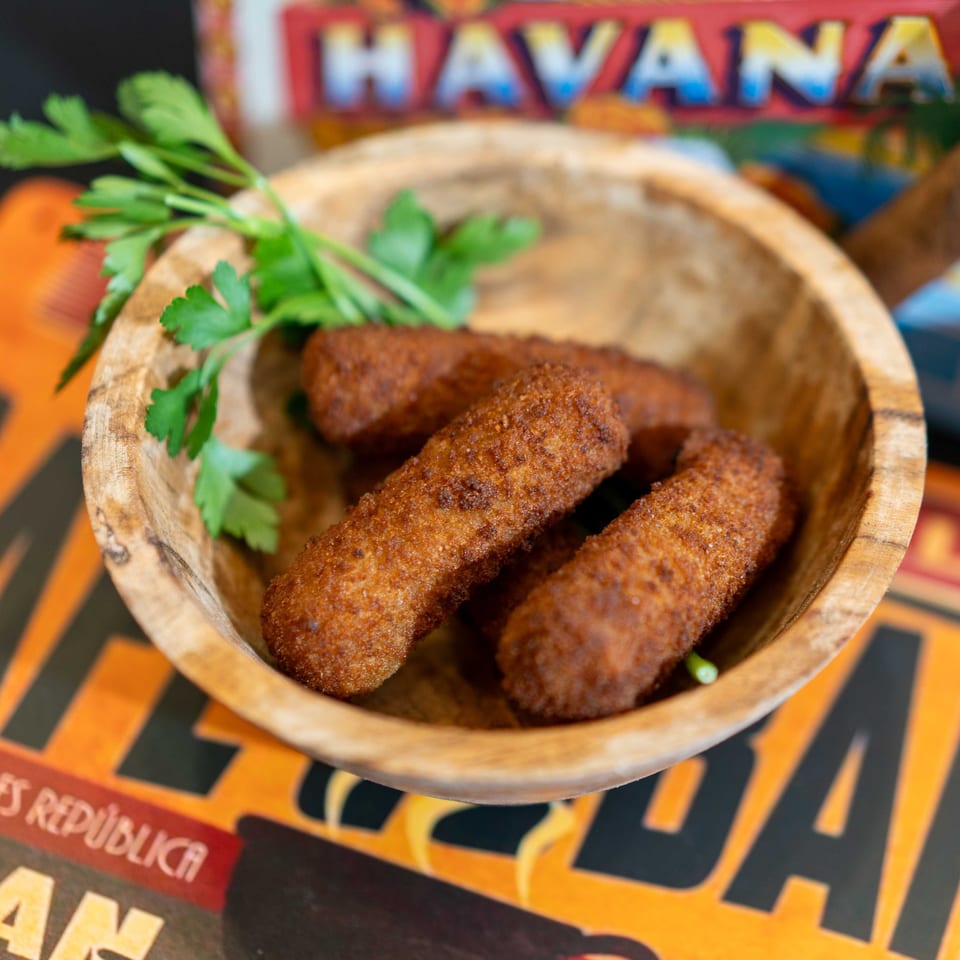 Crispy, golden-brown croquettes garnished with fresh parsley in a rustic wooden bowl.